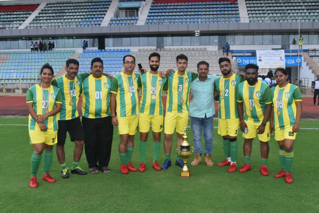 Football team in green and yellow striped kits posing on the pitch with a trophy at their feet.