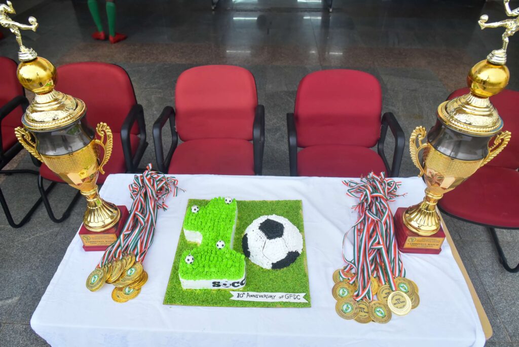 Anniversary trophies, winners’ medals and a football-themed cake reading 10th Anniversary of GFDC.